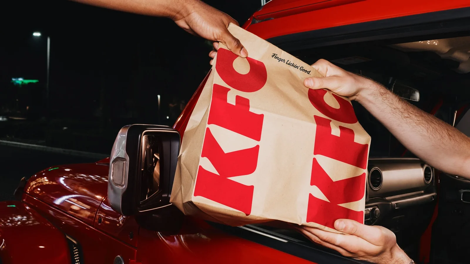 드라이브스루에서 건네지는 KFC 종이봉투 — 새 로고타입 적용