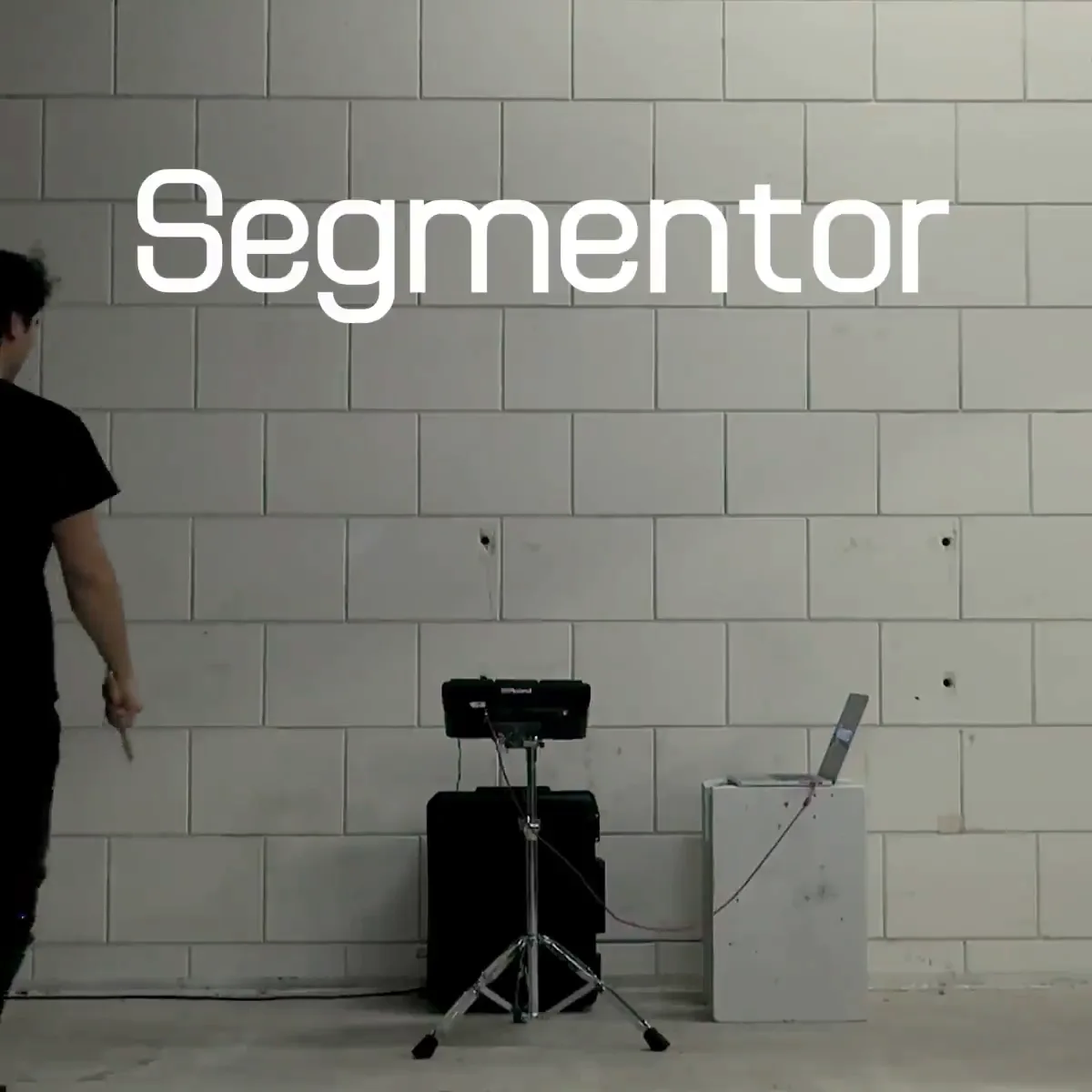 벽돌 벽 앞에서 드럼 패드를 치는 디자이너와 화면에 뜬 Segmentor 글자
