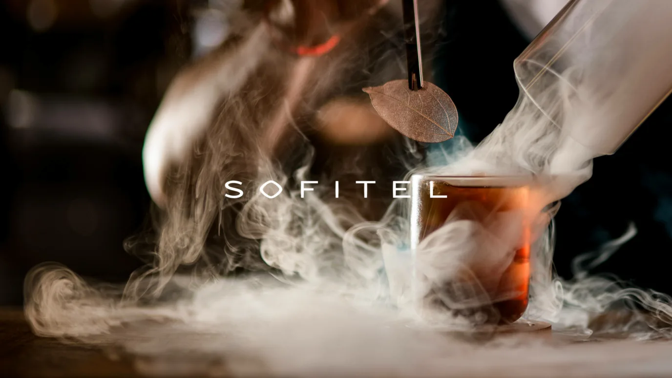 연기가 피어오르는 칵테일 위의 SOFITEL 로고
